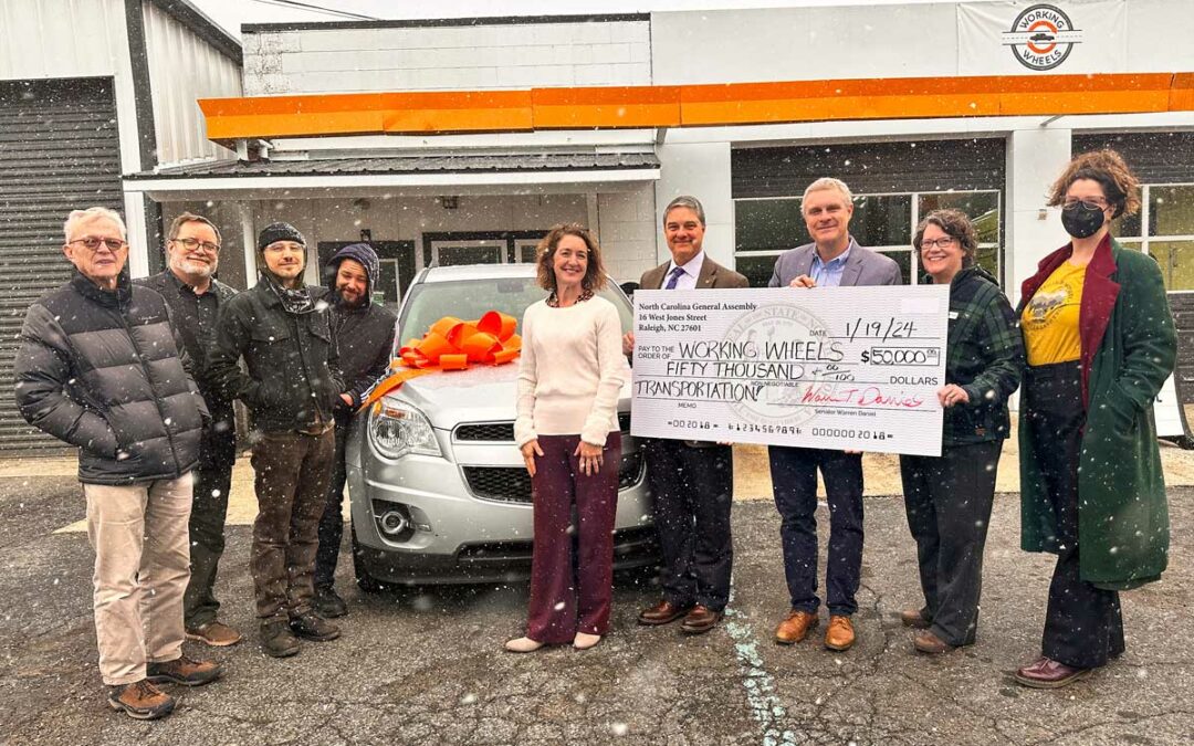 group of people holding big check outside the Working Wheels organization
